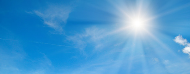 In the blue sky bright sun and light clouds. Wide photo.