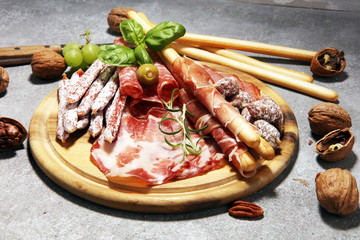 Taca z jedzeniem z pysznym salami, szynką, świeżymi kiełbaskami i ziołami. Mięsny półmisek z wyborem na nieociosanym tle