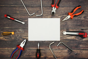 Narzędzia dla majsterkowiczów i biały papier na drewnianym tle