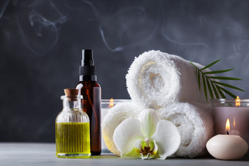 Aromaterapia, spa, zabiegi kosmetyczne i wellness z olejem do masażu, kwiatami orchidei, ręcznikami, produktami kosmetycznymi i płonącymi świecami.