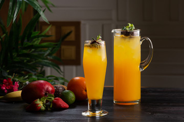 Mangowa lemoniada - pasyjna owoc w dzbanku i owoc na ciemnym drewnianym tle i szkło