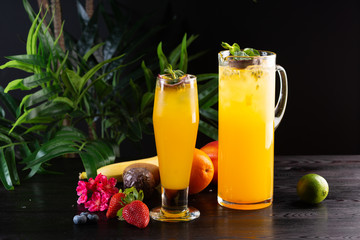 Mangowa lemoniada - pasyjna owoc w dzbanku i owoc na ciemnym drewnianym tle i szkło