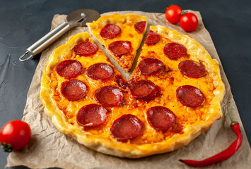 Smakowita pepperoni pizza pomidory i składniki na betonowym tle.