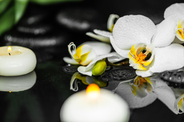 spa martwa biała orchidea (phalaenopsis), świece i czarne kamienie zen z kropli na wodzie z refleksji