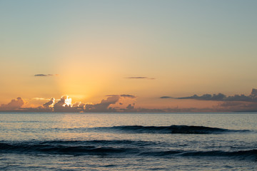 Ostatnie promienie dnia świeciły z chmur, gdy słońce zachodzi na Ocean Spokojny w Maui na Hawajach.