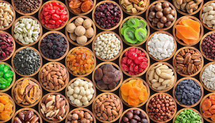 assorted nuts and dried fruit background. organic food in wooden bowls, top view.