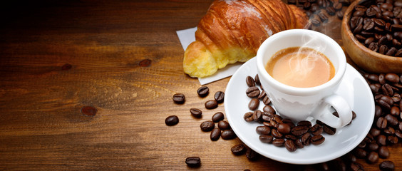 Kawa espresso i croissant z kawowymi fasolami na drewnianym tle