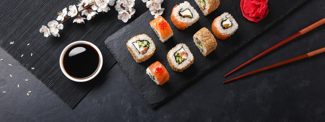 Zestaw sushi i maki rolki z gałęzi białych kwiatów na stole z kamienia