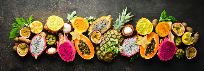Owoce tropikalne na brązowym tle: papaja, mangostan, owoc kaktusa, pytahaya, ananas. Widok z góry. Wolne miejsce na tekst.