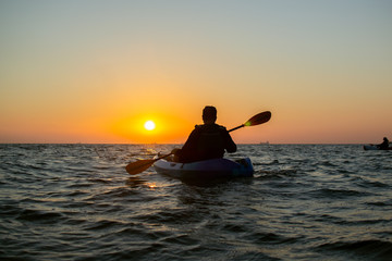 On a warm summer morning, a person meets the sunrise and kayaks. Sports concept