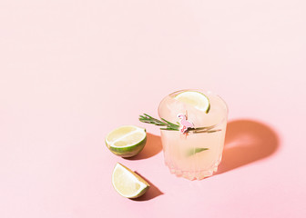 A refreshing drink of lemon and lime lemonade transparent glass on a pink background bright sunlight. Summer cocktail