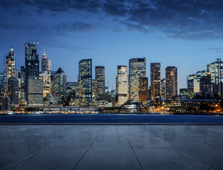 Pusta droga, chodnik z miastem nocą w tle.