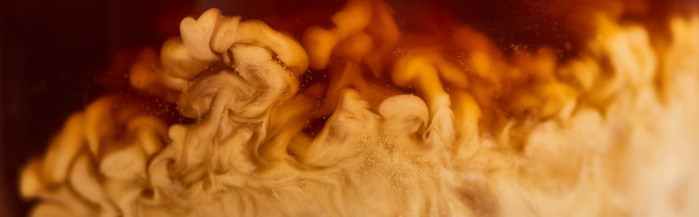 close up view of coffee mixing with milk in glass, panoramic shot