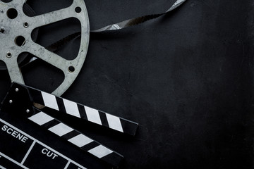 Go to the cinema with film type and clapperboard on black background top view mock up