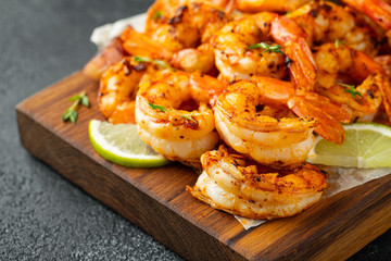 Grilled shrimps or prawns served with lime, garlic and white sauce on a dark concrete background. Seafood