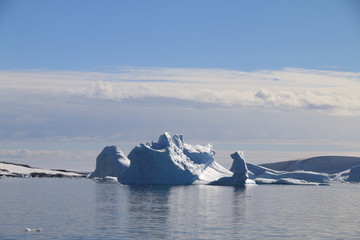 wystający ponad taflę wody wierzchołek góry lodowej przy wybrzeżu antarktydy w słoneczny dzień