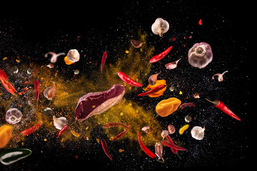 Ostra czerwona papryka, czosnek, różne przyprawy w proszku paliki mięsne latające na czarnym tle Kompozycja zdjęć Motion freeze