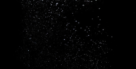 Blurry images of soda water bubbles splashing and floating up to top of water surface which little and big circle texture shaped up by gas power in carbonate drink make refreshing moment on black