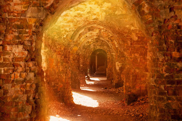Ruins of an ancient medieval ruined castle in sun rays. Arch background.