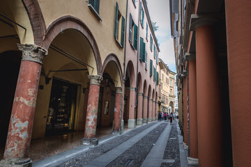 Narrow street with porticoes in historic part of Bologna, Italy