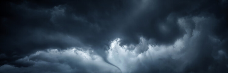 The typhoon is born, a tornado in a stormy dark sky with black clouds .Panoramic image. Concept on the theme of weather, natural disasters, tornadoes, typhoons, tornadoes, thunderstorm.