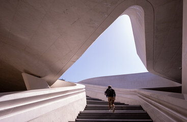 Unrecognised person walking at the stairs leading to a bright open space.
