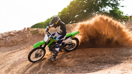 Young man practice riding dirt bike.Splashing sand