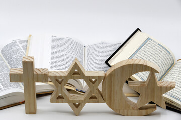 The three monotheistic religions. Christianity, Islam and judaism. Thorah, Quran and Bible with croos, star of David and muslim crescent. Interreligious or interfaith symbols. France.