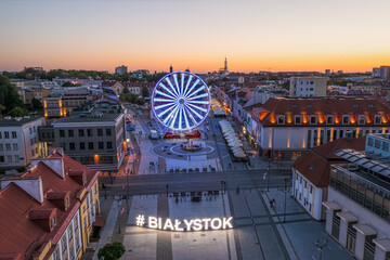 Białystok, widok z lotu ptaka o zmierzchu na Ratusz, Rynek Kościuszki, koło widokowe i napis #Białystok