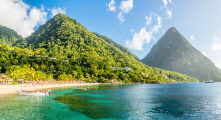 Caribbean beach with palms and straw umrellas on the shore with Gros Piton mountain in the background, Sugar beach, Saint Lucia