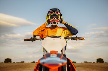 Portrait of motocross rider taking off helmet