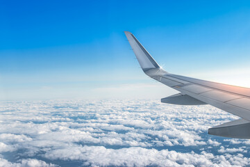 Airplane wing above the clouds. View from airplane window. Air travel and transportation concept. 