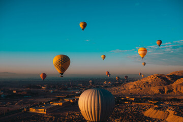 Wide view of dozens of hot air balloons flying around the luxor egypt area. Popular tourist activity, amazing view of the surrounding desert area