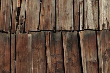 Close-up of weathered wooden planks forming an old wall or roof. Natural texture of aged wood with visible grain, cracks, and rustic character