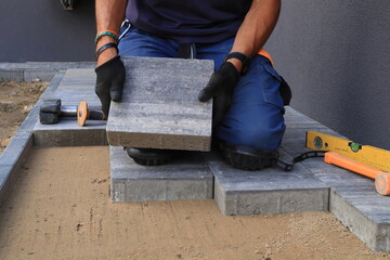 Brukarz, majster układa kostkę.