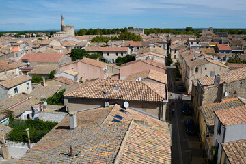 Mury obronne i starożytne miasto, ciasne uliczki, stłoczone domy, czerwone dachy, zielona roślinność na ulicach.