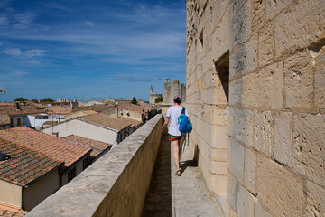 Mury obronne i starożytne miasto, ciasne uliczki, stłoczone domy, czerwone dachy, zielona roślinność na ulicach.
