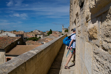 Mury obronne i starożytne miasto, ciasne uliczki, stłoczone domy, czerwone dachy, zielona roślinność na ulicach.