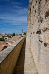 Mury obronne i starożytne miasto, ciasne uliczki, stłoczone domy, czerwone dachy, zielona roślinność na ulicach.