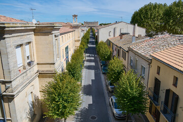 Mury obronne i starożytne miasto, ciasne uliczki, stłoczone domy, czerwone dachy, zielona roślinność na ulicach.