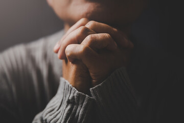 Christ religion and christianity worship or pray concept. Christian catholic woman are praying to god in dark at church. Prayer person hand in black background. Girl believe and faith in jesus christ.
