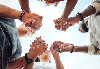 Holding hands, support and friends praying for spiritual growth, community and gratitude together with sky from below. Group of people in partnership for hope, love and human faith in connection