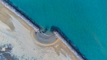 Aerial shot of the beach of Bibione, Venice. Crystal clear water and white rocks. Golden beach and circular shapes. Heaven on earth in Italy, near the Tagliamento river.