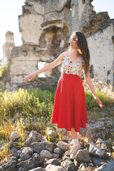 a beautiful girl in a red skirt among the ruins of the old town