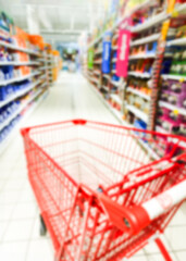 Baner reklamowy, rozmazane tło, background, wnętrze sklepu, supermarketu, wózek na zakupy, półki sklepowe z produktami. Miejsce na tekst.