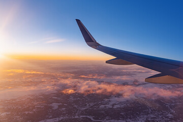 Airplane flying low over snowy mountains and preparing for landing to the airport, view from plane window of wing turbine and skyline