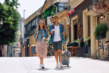Young happy couple walking through town while enjoying in summer trip.