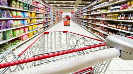 Pusty koszyk, wózek sklepowy w supermarkecie, rozmazane tło, wnętrze sklepu, supermarketu, wózek na zakupy, półki sklepowe z produktami. Hipermarket. Miejsce na tekst.