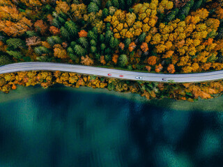 Aerial view of coastline road with autumn fall color woods and blue lakes water in Finland.
