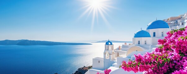 Whitewashed Greek island architecture with blue domes and blooming pink flowers against a bright blue sky and sparkling sea.